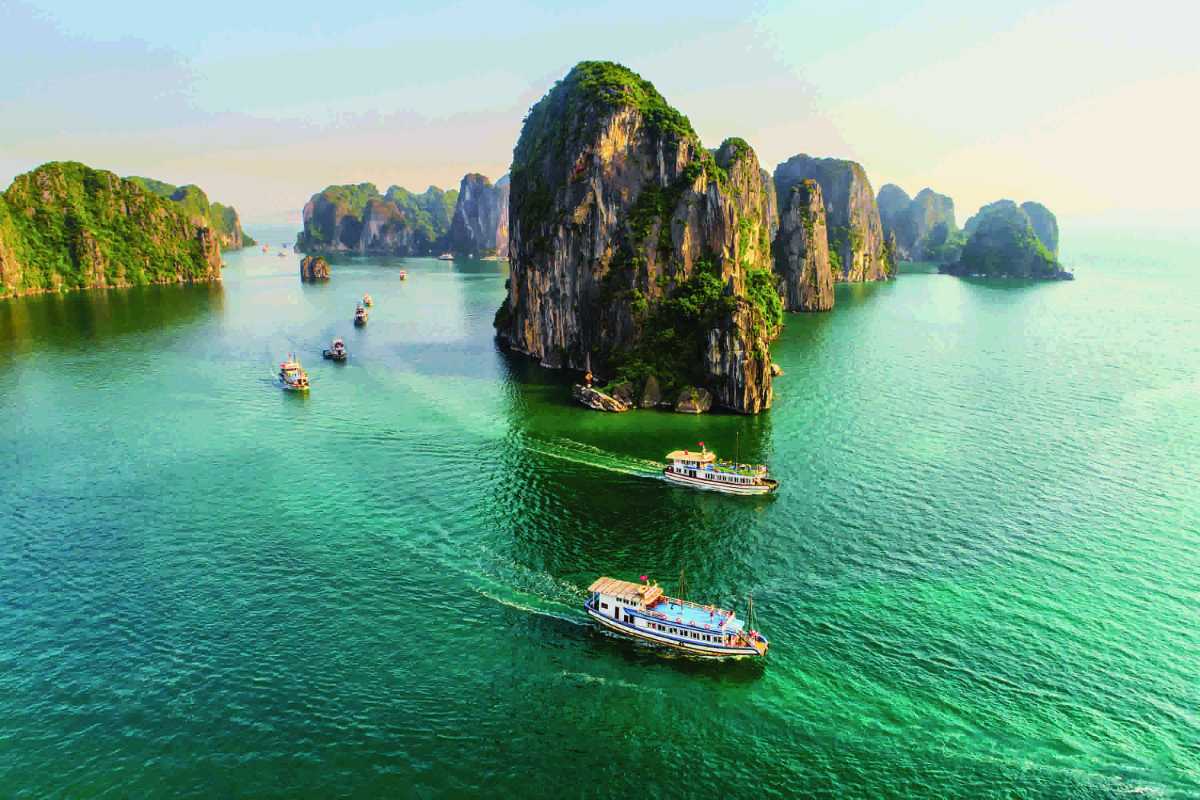 Scenic aerial view of Halong Bay with numerous boats Aerial view showing numerous boats and islands in Halong Bay near the famous Drum Cave attraction.