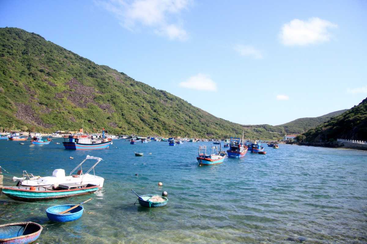 Scenic Bay Near Mot Island Blue and red fishing boats floating on turquoise waters between lush green hills near Mot Island.