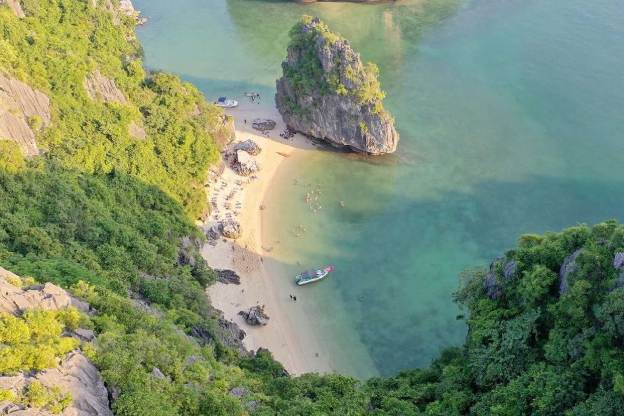 Visitors swimming and enjoying the peaceful cove at Ba Trai Dao Beach, surrounded by limestone cliffs in Lan Ha Bay.