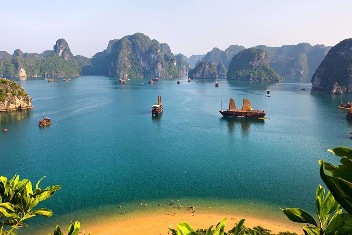 A breathtaking view of Quan Lan Island in Bai Tu Long Bay with boats on the water and lush limestone cliffs.