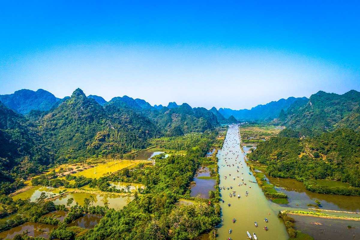 Scenic Red River Vietnam Waterway with Boats Waterway on the Red River Vietnam with boats and green riverbanks under a blue sky