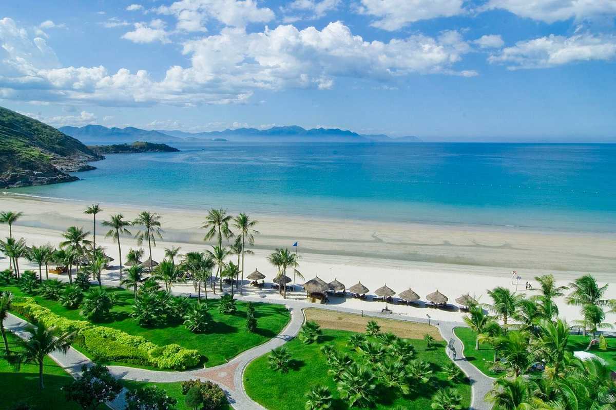 Scenic white sandy beach at Nha Trang Bay Wide white sandy beach at Nha Trang Bay lined with palm trees and sun umbrellas