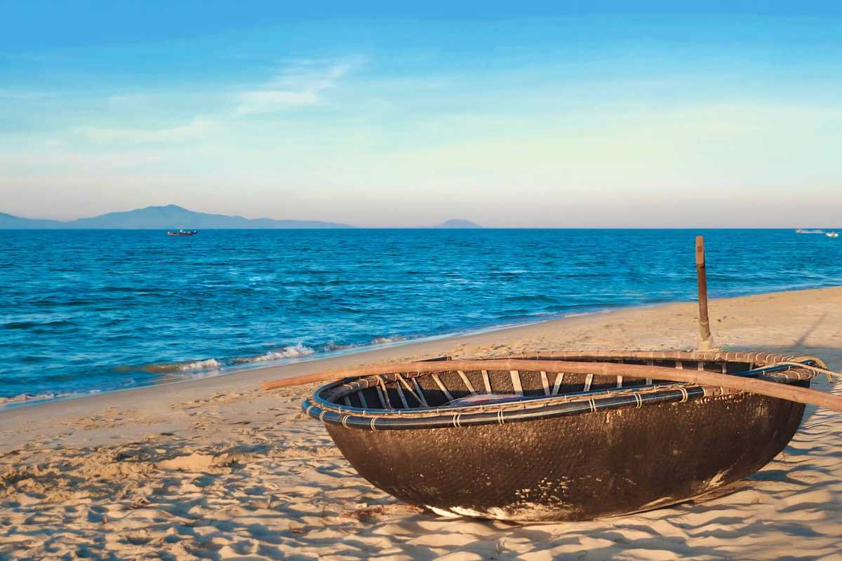 Serene Traditional Basket Boat on Cua Dai Beach Traditional basket boat resting on the sandy shore of Cua Dai Beach under a clear blue sky