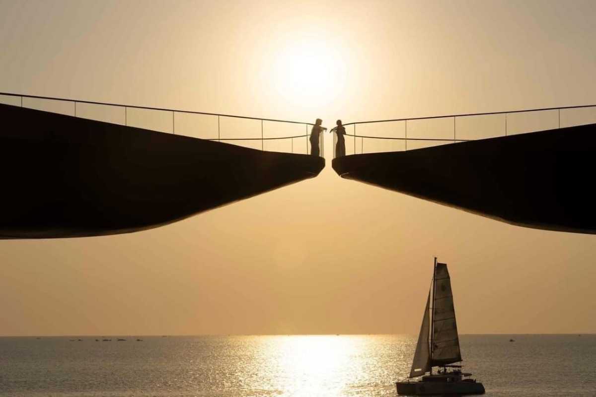 Silhouette on Kiss Bridge at Sunset Phu Quoc Silhouetted figures standing on Kiss Bridge with sun setting over the sea on Phu Quoc