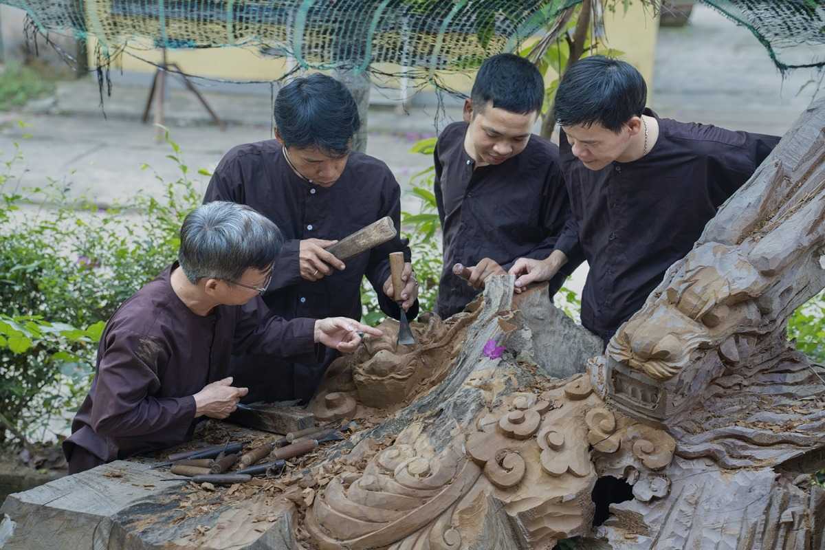Skilled Artisans Working on Wood Carvings at Kim Bong Group of artisans collaborating on detailed wood carvings outdoors at Kim Bong Carpentry Village