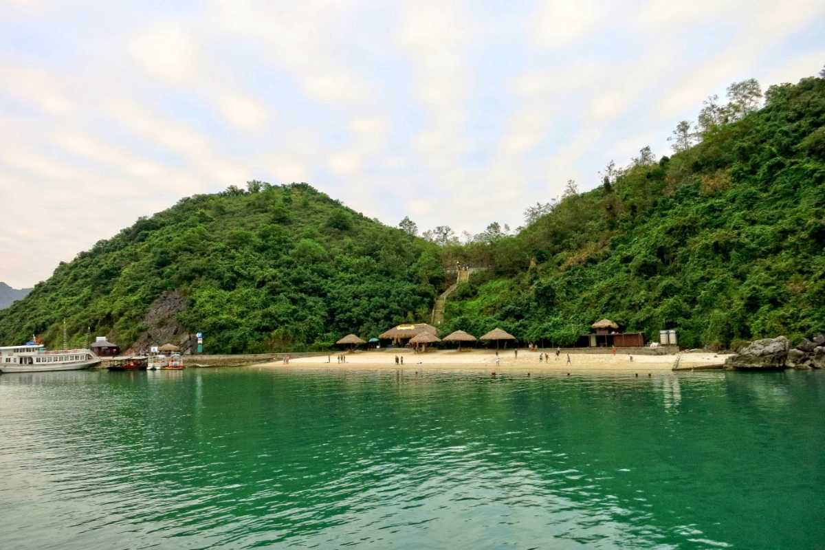 Soi Sim Island Halong Bay Scenic View from the Water A scenic view of Soi Sim Island Halong Bay beach from the water with lush green hills and sandy shore