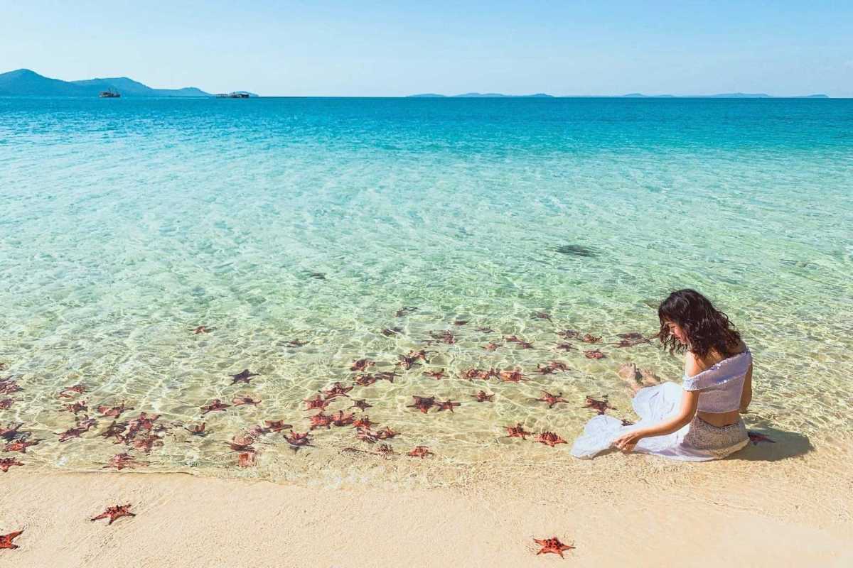 Starfish Beach Phu Quoc couple walking in shallow water Couple walking hand in hand in shallow clear water at Starfish Beach Phu Quoc