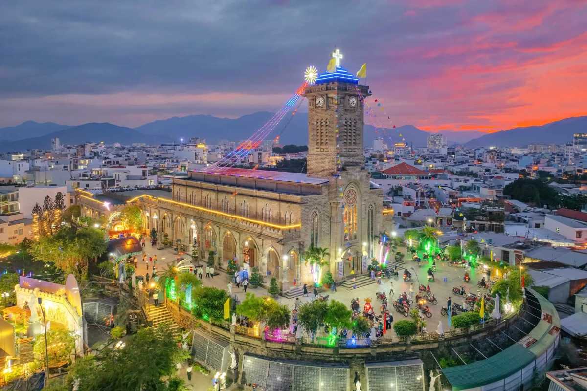 View of Stone Church Nha Trang Cathedral illuminated at sunset with city skyline and mountains