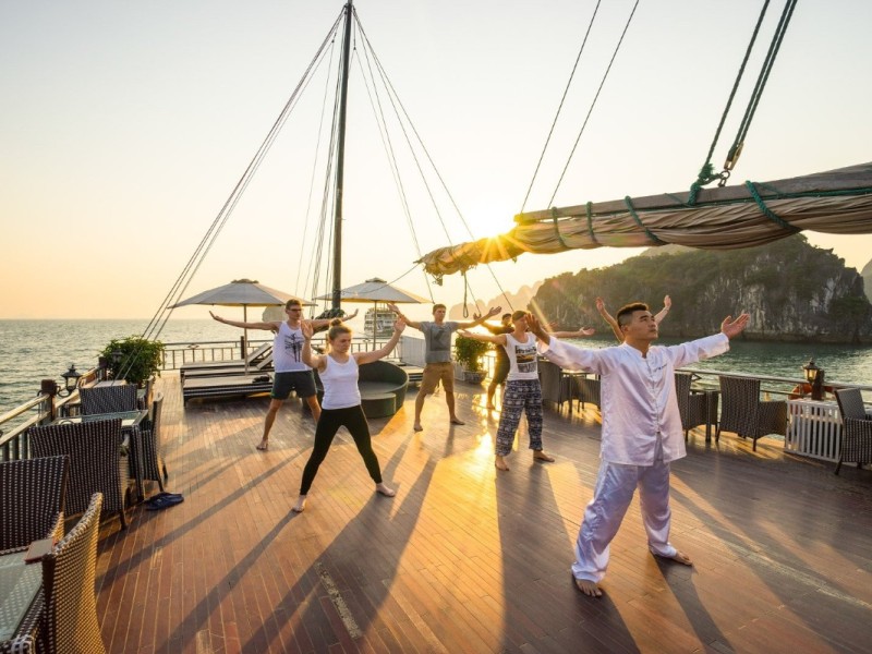 Sunrise Tai Chi session on a Halong Bay cruise with scenic limestone karsts in the background.