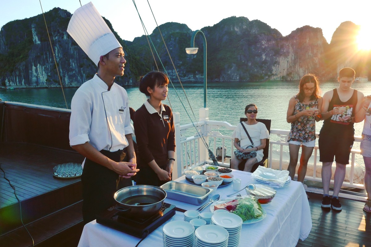 Guests enjoying a sunset cooking class on a Halong Bay cruise.