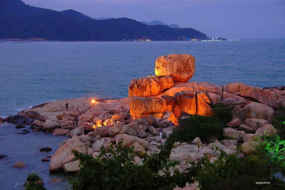 Hon Chong Promontory at sunset with illuminated rocks Hon Chong Promontory rocks illuminated at dusk with ocean waves nearby