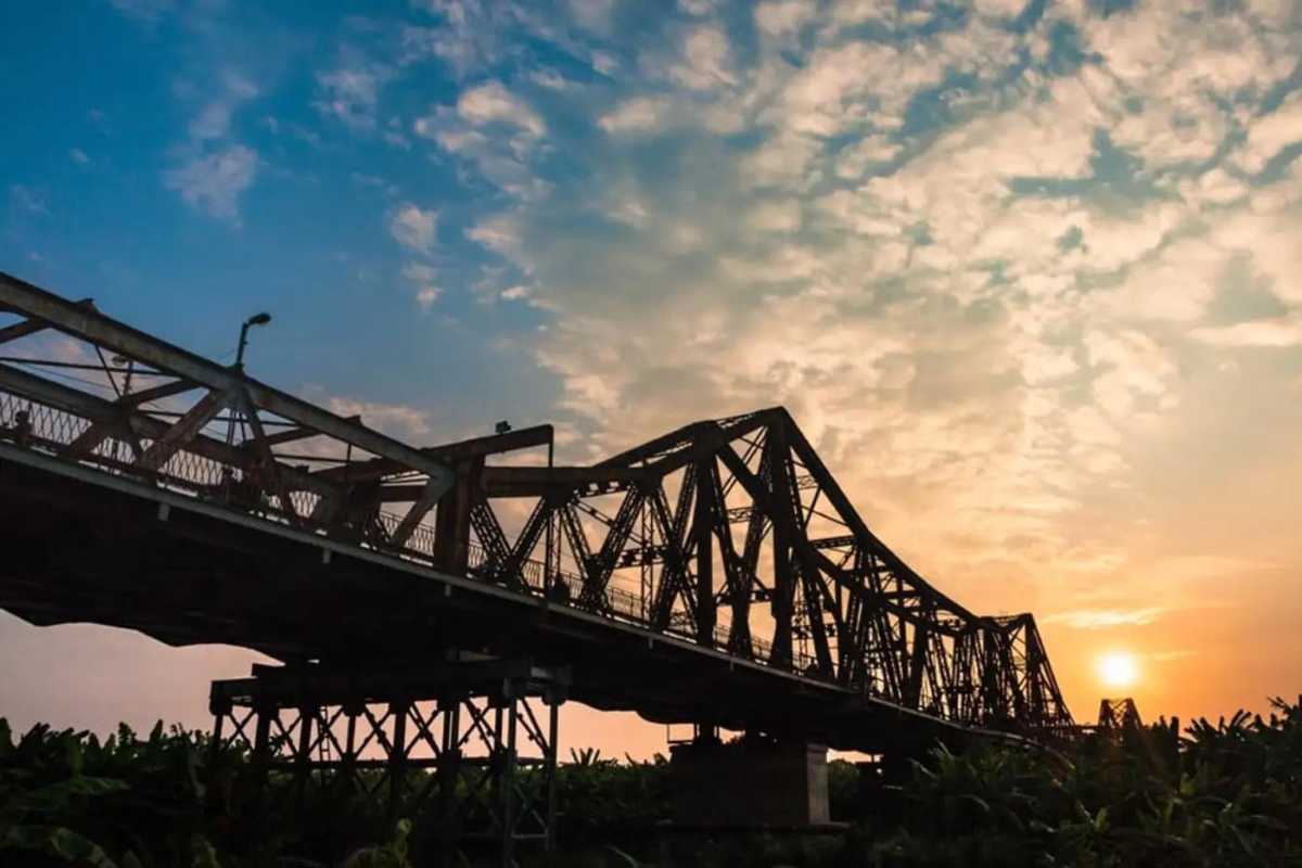 Sunset Silhouette of Long Bien Bridge Silhouette of Long Bien Bridge at sunset with orange sky and river reflection