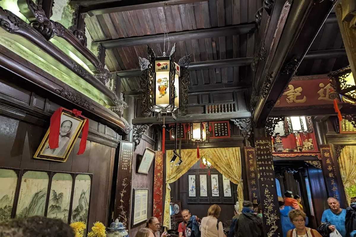Visitors Exploring Tan Ky Ancient House Interior Visitors exploring the detailed interior exhibits of Tan Ky Ancient House in Hoi An