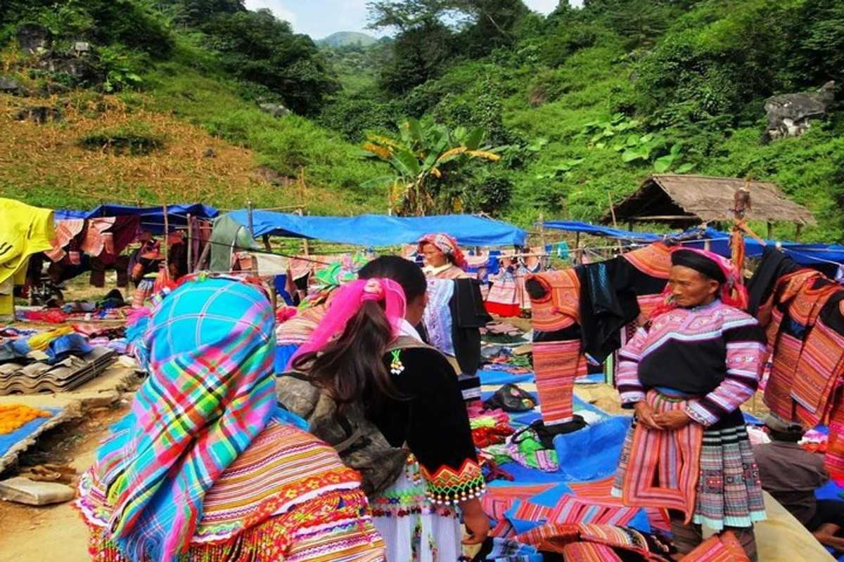 Textile market scene at Coc Ly in the hills Ethnic groups gather at hillside stalls of Coc Ly Market surrounded by colorful textiles and mountainous backdrops.