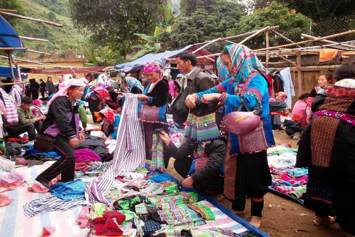 Colorful textile shopping at Coc Ly Market Shoppers browse bright fabrics and traditional garments at Coc Ly Market in a remote mountain village of Vietnam.