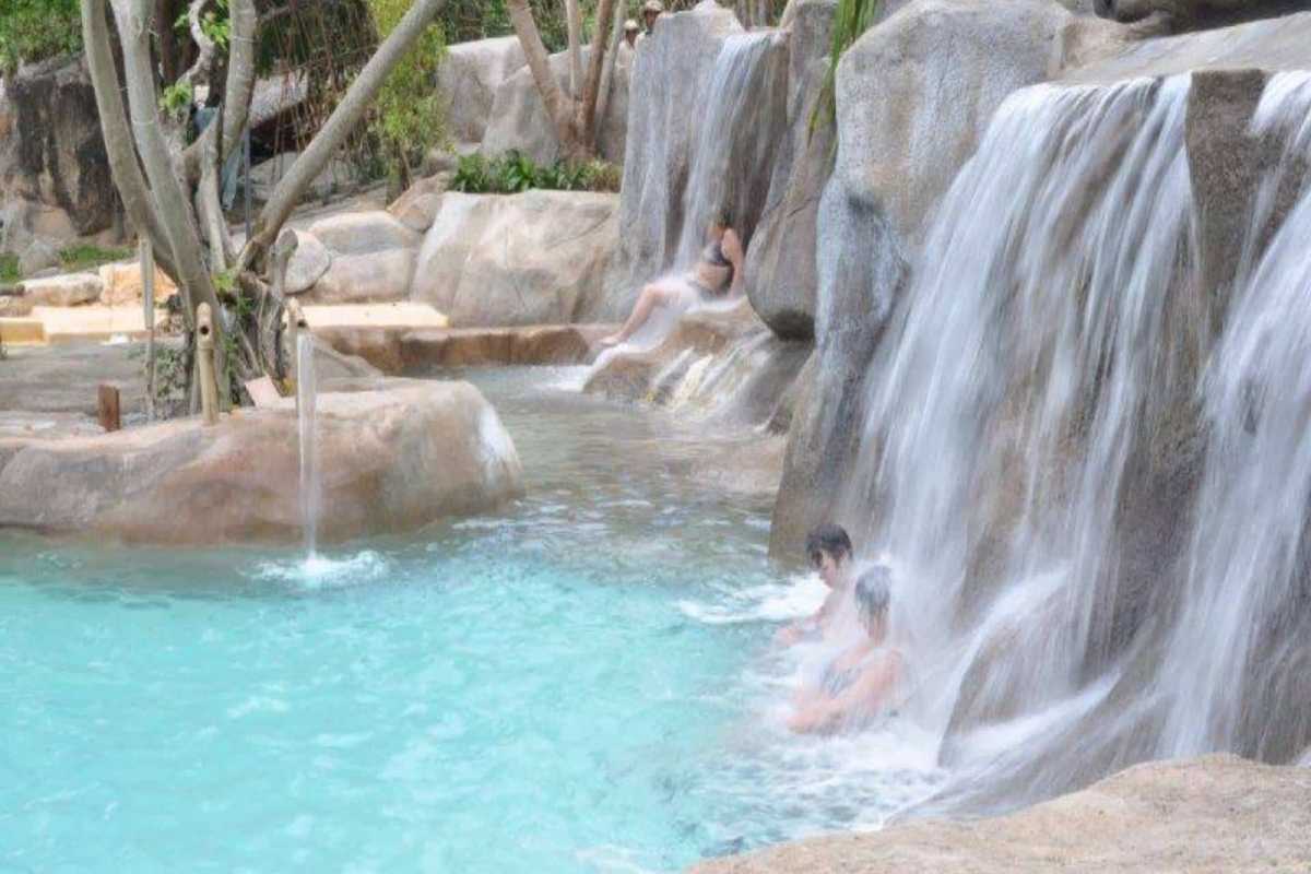 Visitors relax beneath cascading waterfalls at Thap Ba Hot Springs, enjoying natural hydrotherapy in Nha Trang
