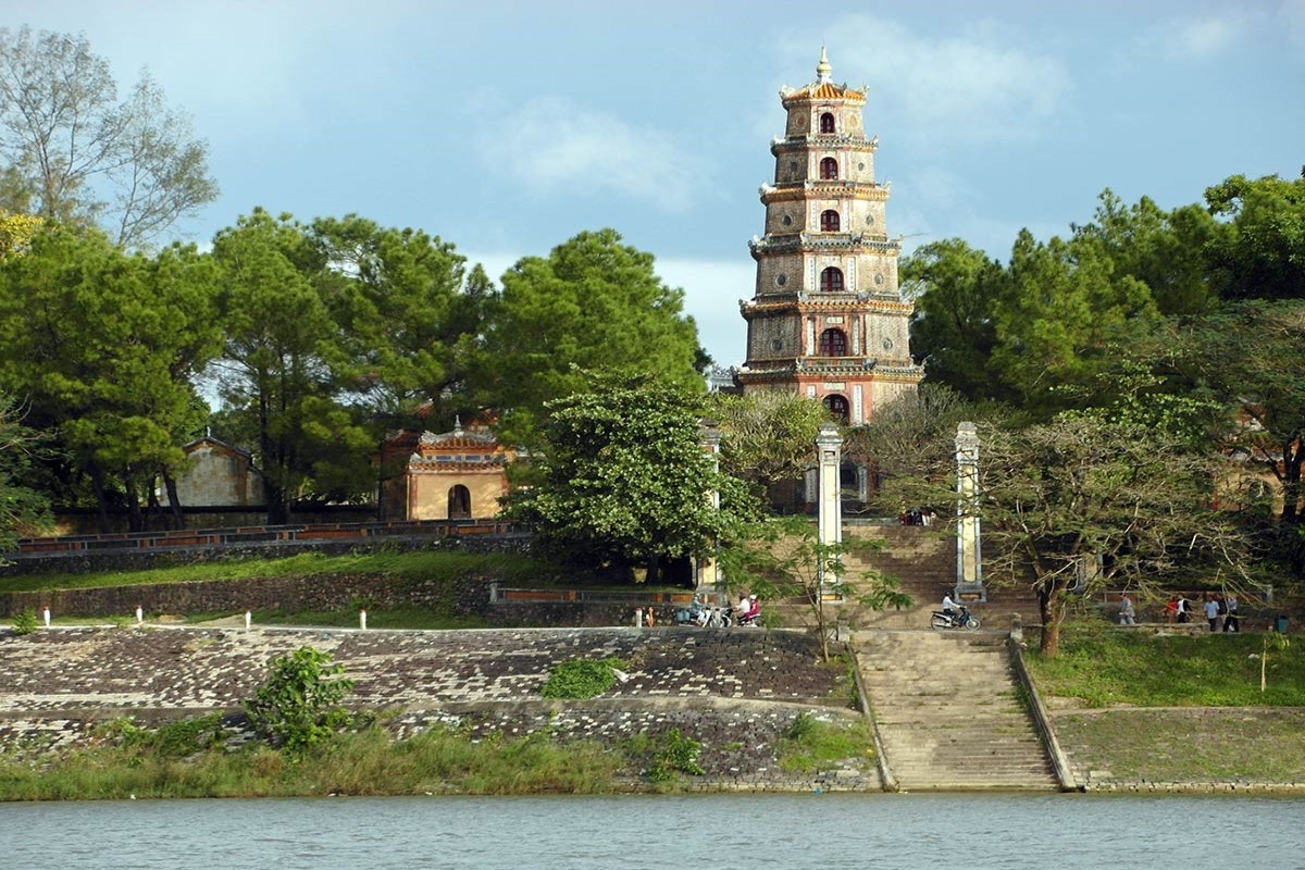 A view of Thien Mu Pagoda from the Perfume River in Hue, Vietnam, showcasing its serene location.