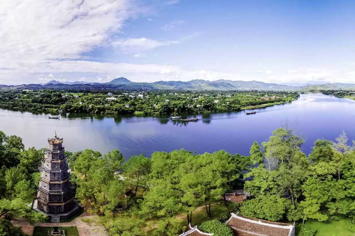 Thien Mu Pagoda’s riverside view over the Perfume River in Hue Riverside panorama from Thien Mu Pagoda shows the Perfume River, lush hills, and peaceful scenery, highlighting the beauty of Hue.