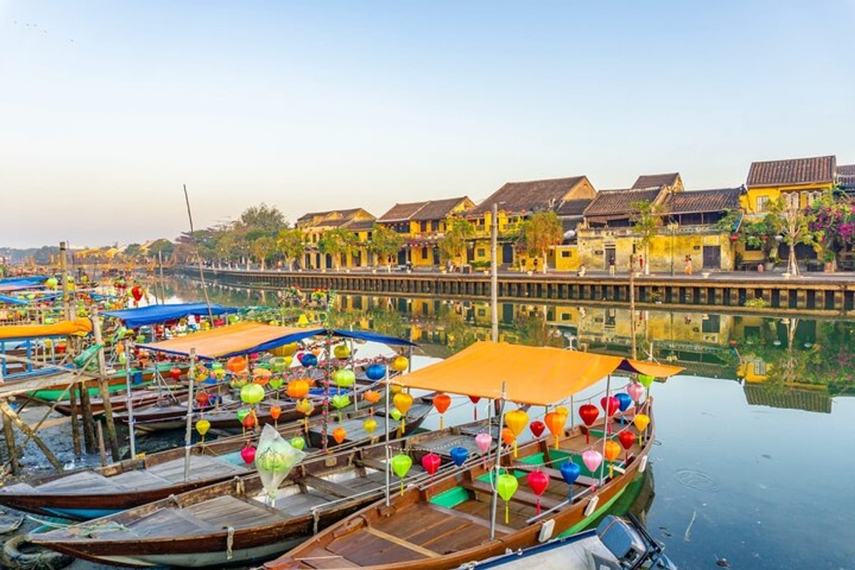 Thu Bon River in Hoi An featuring colorful boats and traditional yellow buildings along the riverbanks.