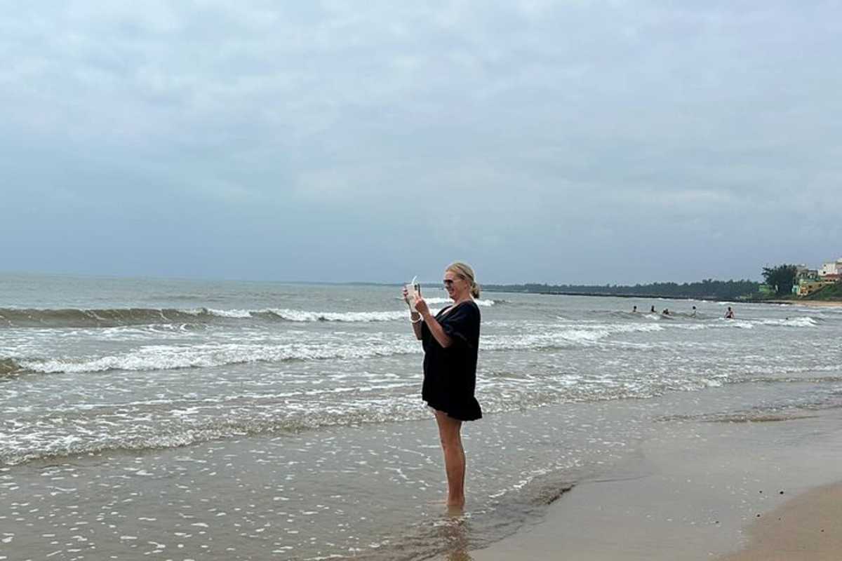 Thuan An Beach Hue early morning visitor wading at shoreline Thuan An Beach Hue features a traveler standing at the water’s edge, enjoying peaceful waves under cloudy skies with a tranquil seascape.