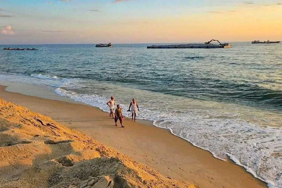 Thuan An Beach Hue sunset stroll along golden sandy shoreline Thuan An Beach Hue at sunset with visitors walking beside calm waves and soft golden sands, soaking in the evening light and tranquil scenery.