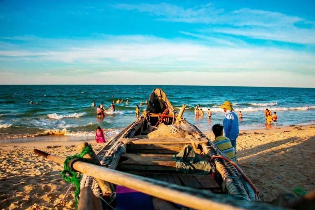 Thuan An Beach Hue wooden fishing boat and families by the surf Thuan An Beach Hue captures a traditional wooden fishing boat on the shore with families playing in the waves, celebrating the region’s culture and joy.