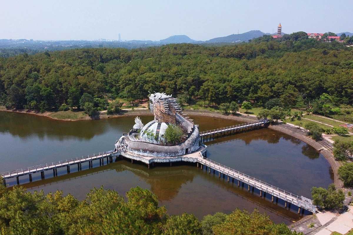 Thuy Tien Lake Dragon Statue on Water Dragon statue rising above Thuy Tien Lake with walkways, surrounded by forested hills near Hue's haunted abandoned water park