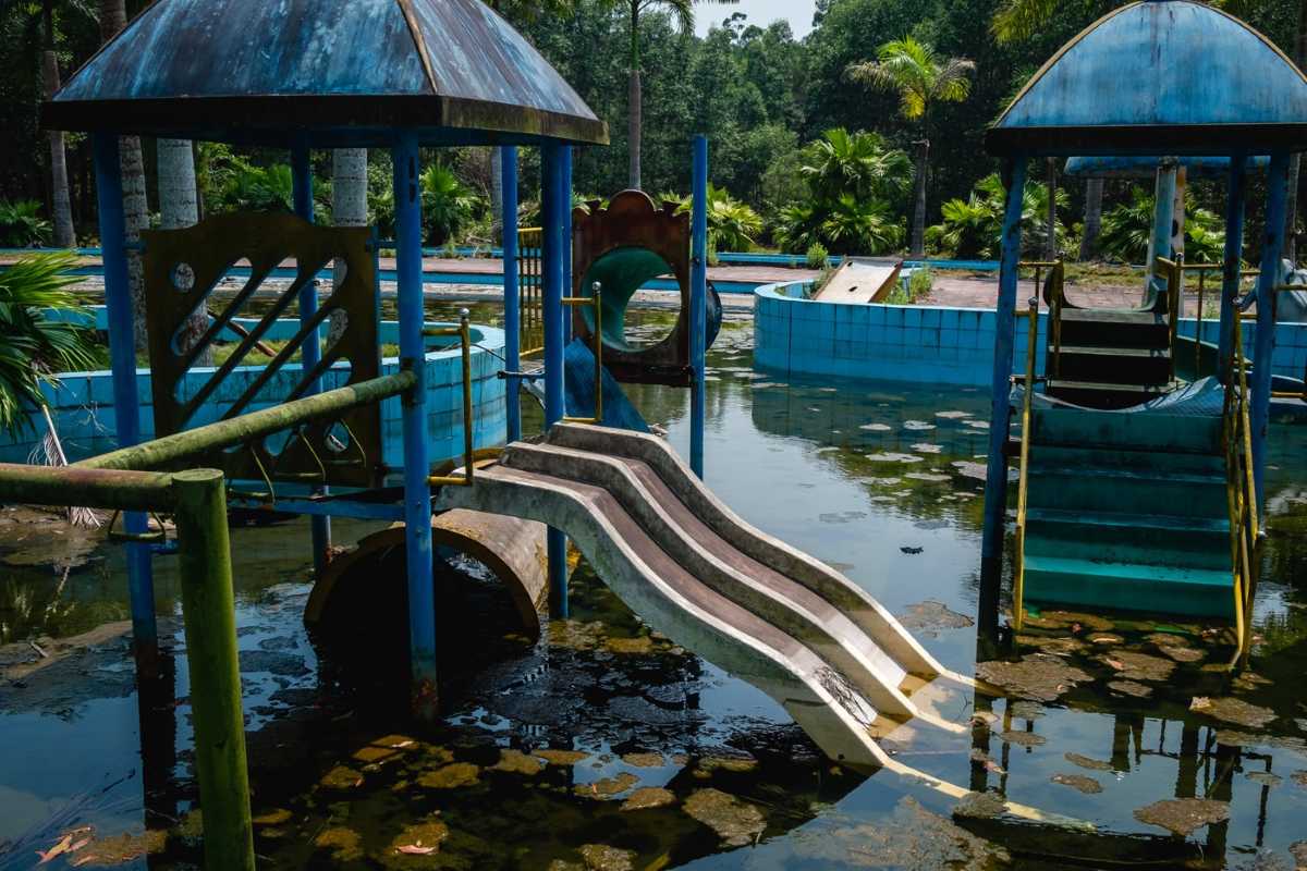Forgotten Playground at Thuy Tien Lake Mossy, unused playground equipment sits partially submerged in stagnant water inside Thuy Tien Lake Abandoned Water Park Hue