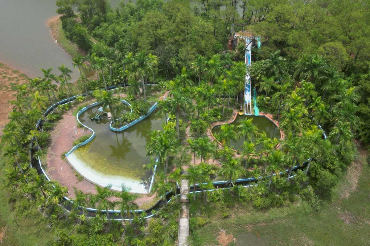 Aerial of Overgrown Water Slides Thuy Tien Lake Hue Two abandoned water slides curve through tropical palms and ponds at Thuy Tien Lake Abandoned Water Park Hue
