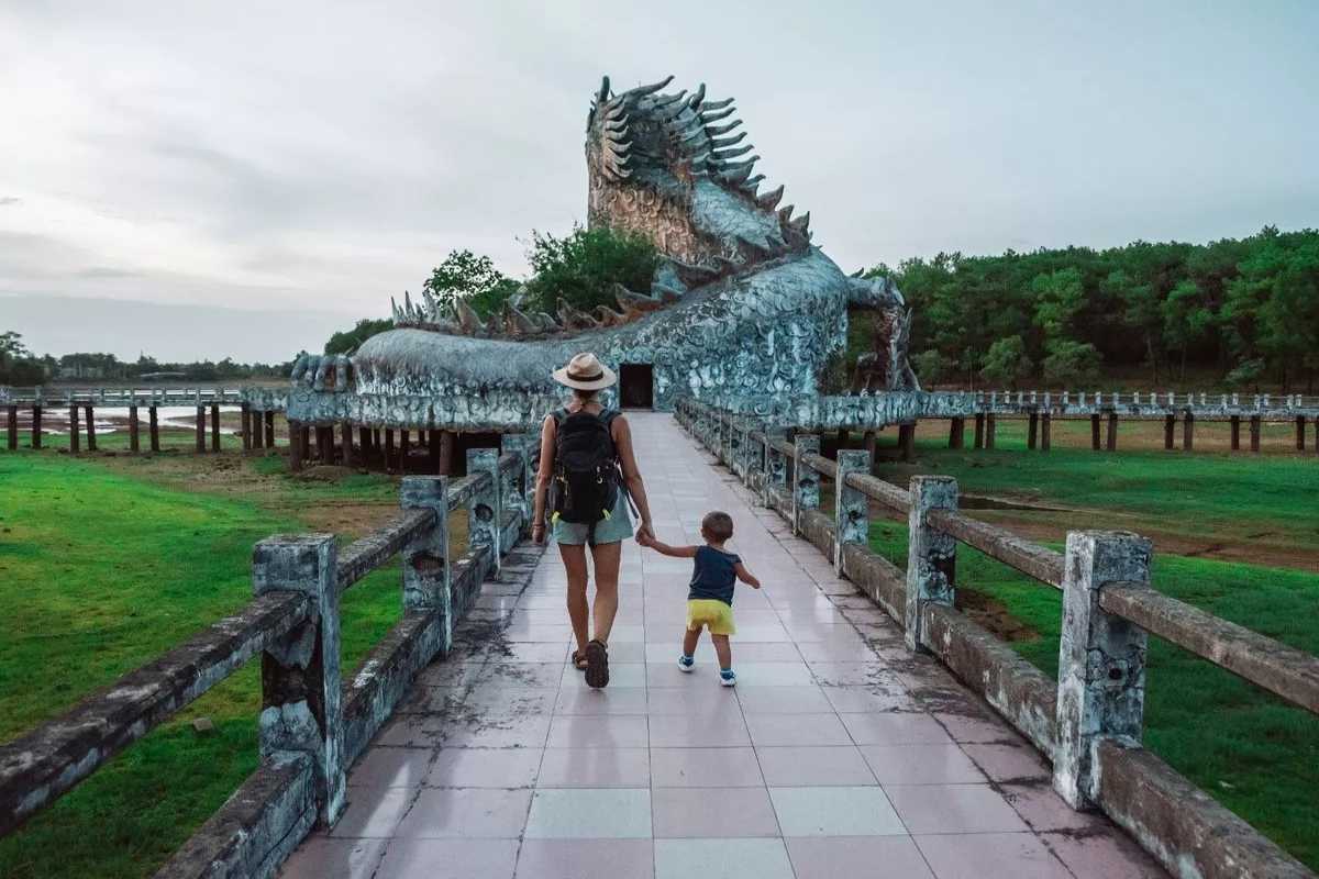 Pathway to Dragon Statue at Thuy Tien Lake Walkway leads toward the dragon statue at Thuy Tien Lake with a woman and child exploring the entrance of the abandoned water park