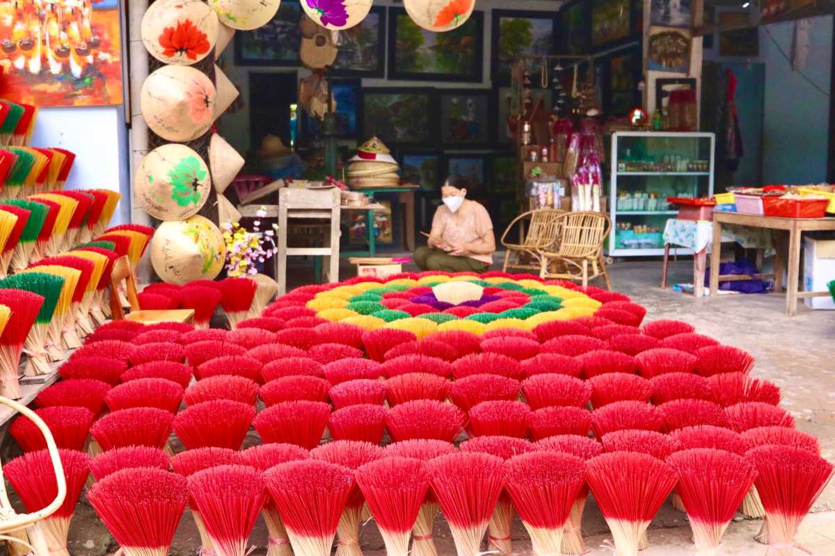 Incense Craft Workshop at Thuy Xuan Incense Village Hue Artisan working among bundles of red, green, and yellow incense sticks inside a traditional shop in Thuy Xuan Village.