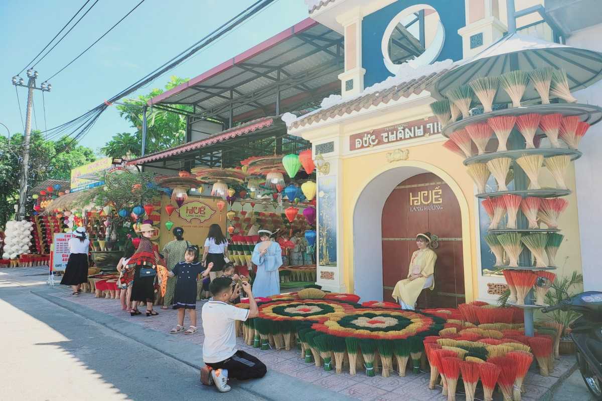 Photo Spot at Thuy Xuan Incense Village Hue Entrance Tourists pose among colorful incense bundles and lanterns by the landmark archway at Thuy Xuan Incense Village Hue.