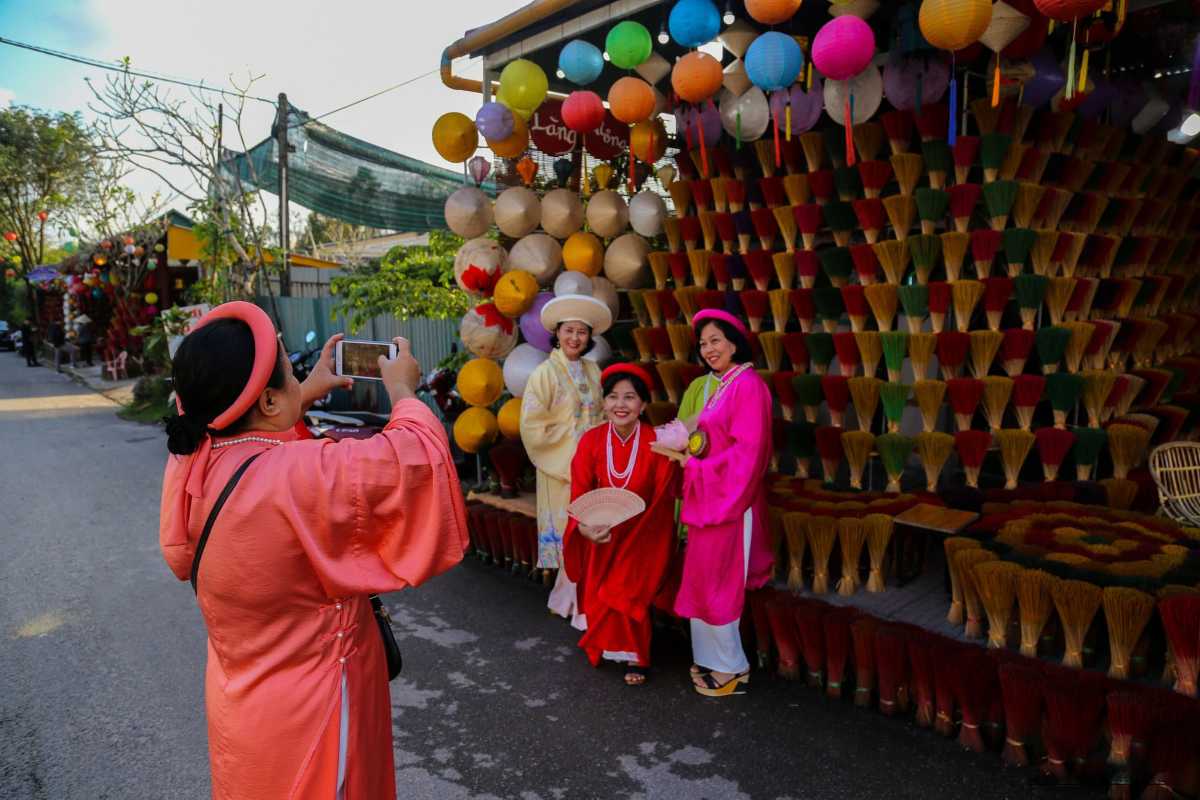 Traditional Dress Photos at Thuy Xuan Incense Village Hue Group in vibrant traditional ao dai takes photos in front of incense stick displays at Thuy Xuan Incense Village in Hue, Vietnam.