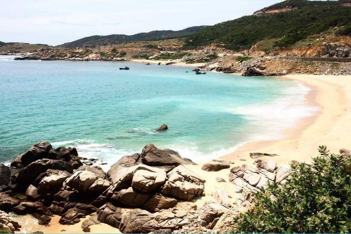 Tien Beach Nha Trang pristine shore with green hills Pristine sandy shore of Tien Beach Nha Trang with clear blue waters and lush green hills in the background.