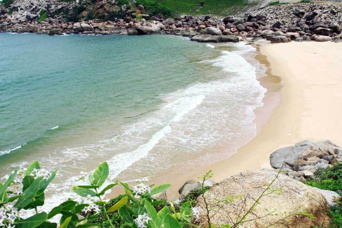 Tien Beach Nha Trang natural rocky coastline Natural rocky coastline and sandy beach at Tien Beach Nha Trang with green hills in the background.
