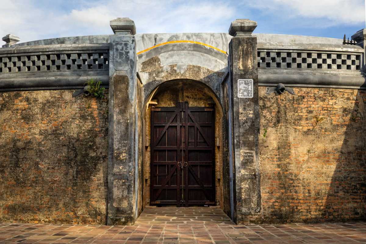 Tiger Arena Hue closeup of fortified wooden entrance door Tiger Arena Hue’s original fortified entrance features a heavy wooden door set in a stone archway, highlighted by historic wall textures.