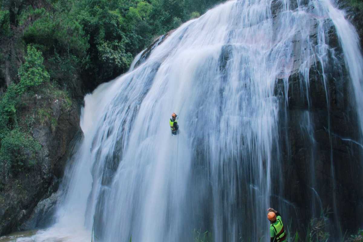 Tiger Waterfall Da Lat Adventure Canyoning Experience Adventurers rappelling down Tiger Waterfall Da Lat surrounded by lush tropical forest and cascading water