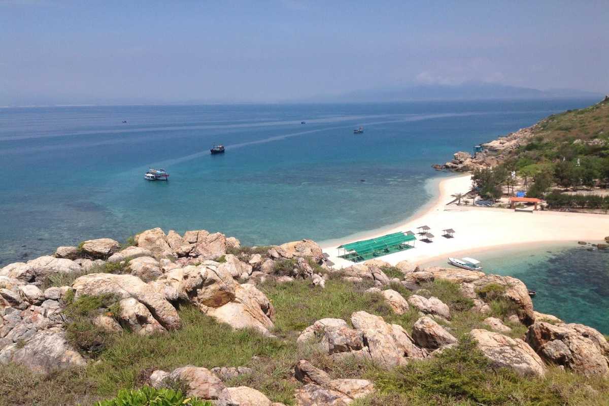 Tourist Cabanas and Crystal Waters Shaded cabanas on the beach of Yen Island Nha Trang with visitors enjoying clear shallow waters.