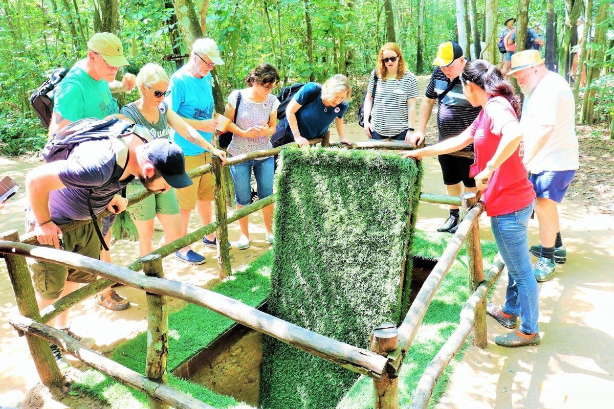 Group of tourists exploring Cu Chi Tunnel entrance in Vietnam