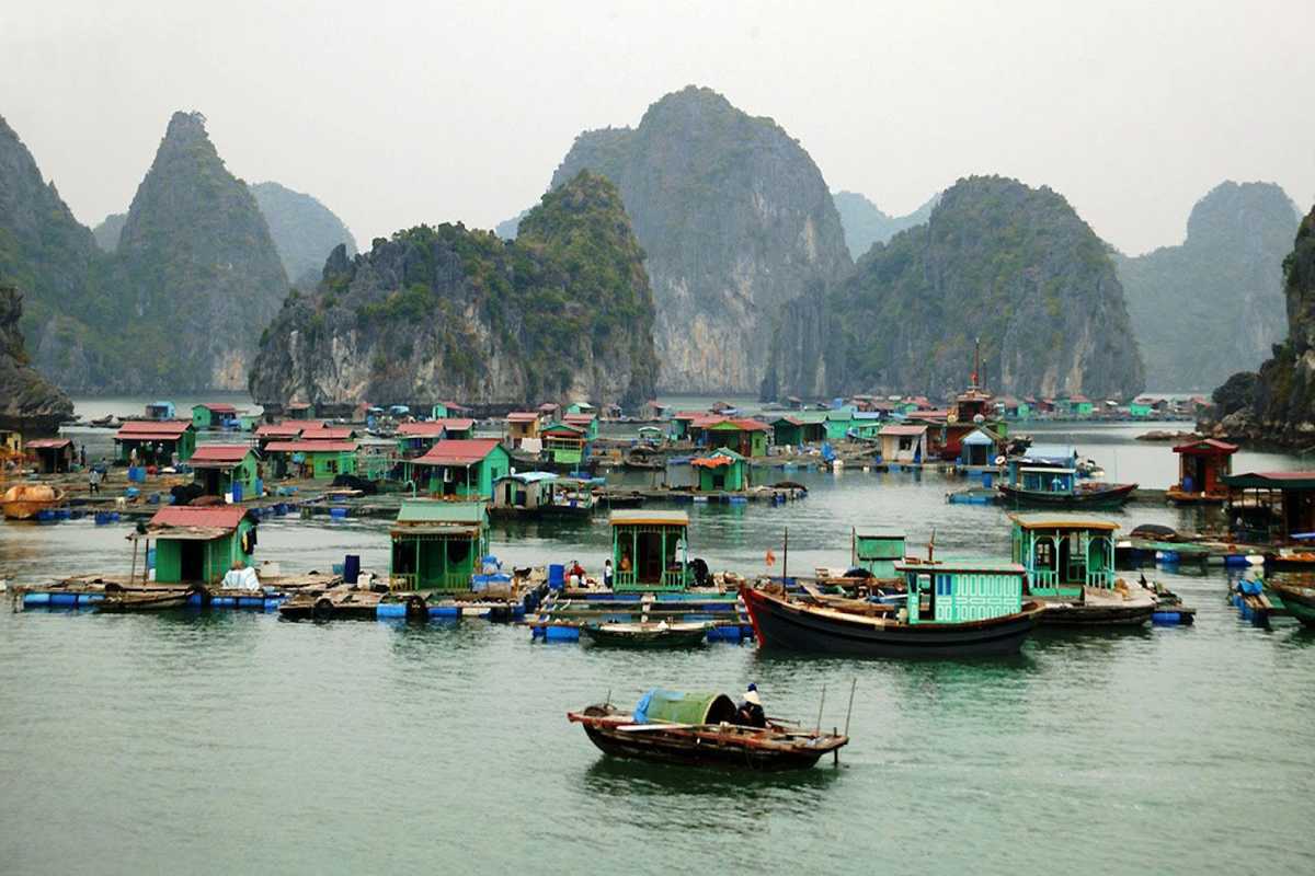 Tourists Exploring Floating Village by Rowboat Tourists on a small rowboat visiting floating houses in Cong Dam Fishing Village