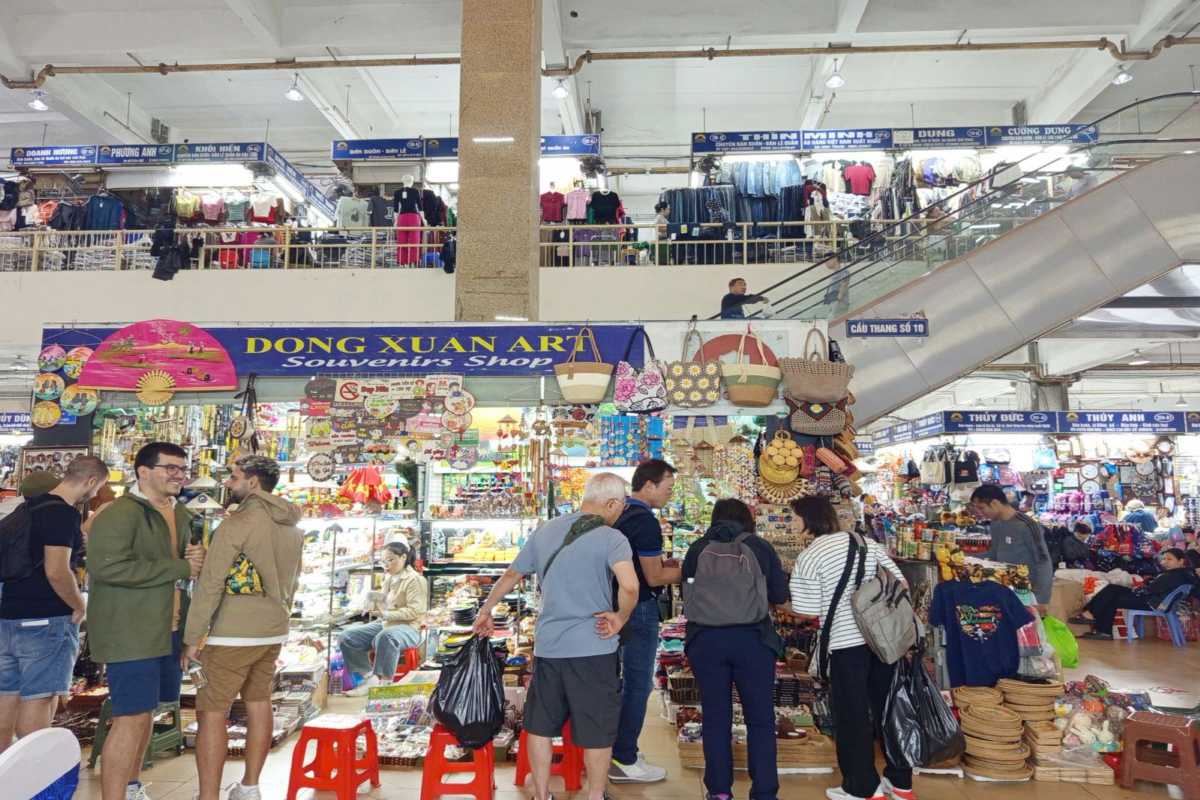 Tourists Shopping at Dong Xuan Market Stalls Tourists browsing unique souvenirs and accessories at popular stalls inside Dong Xuan Market.