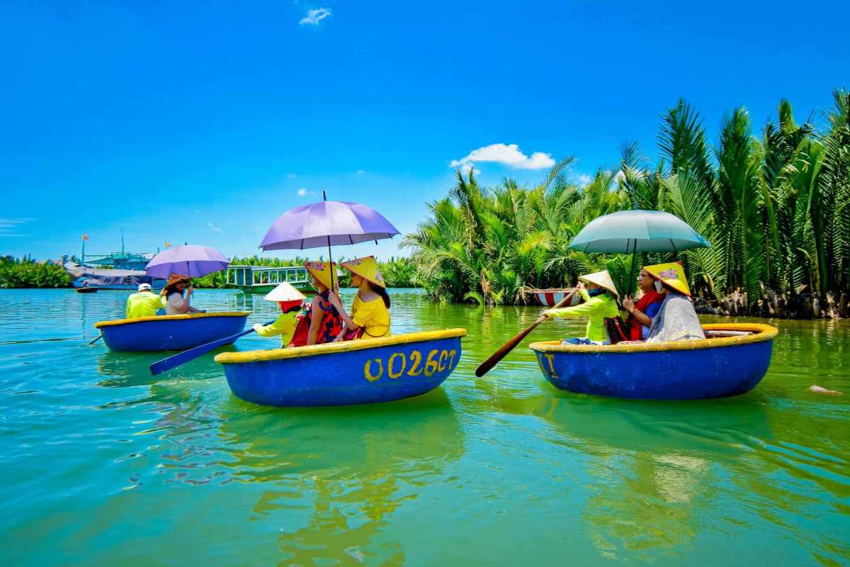 Tourists Using Umbrellas on Basket Boats in Cam Thanh Village Tourists paddling traditional basket boats with umbrellas under blue sky in Cam Thanh Coconut Village