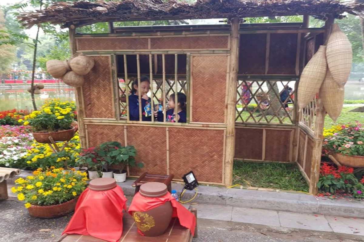 Traditional Bamboo Hut at Ngoc Ha Flower Village Hanoi Children inside a traditional bamboo hut surrounded by flowers in Ngoc Ha Flower Village Hanoi, reflecting cultural heritage.