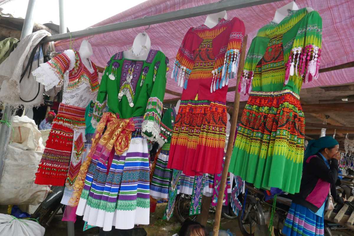 Colorful traditional costumes for sale at Coc Ly Market Brightly patterned traditional dresses on display at Coc Ly Market in Lao Cai, representing ethnic diversity and style.