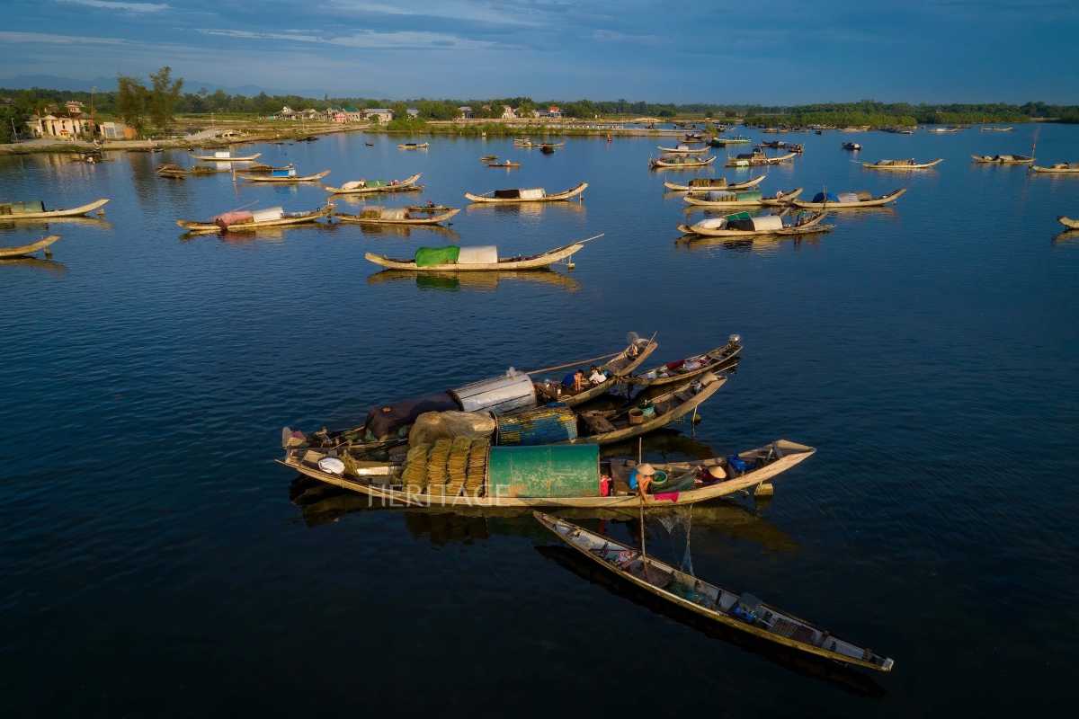 Traditional Fishing Boats on Tam Giang Lagoon Traditional wooden fishing boats floating on calm waters of Tam Giang Lagoon under a purple sunset sky