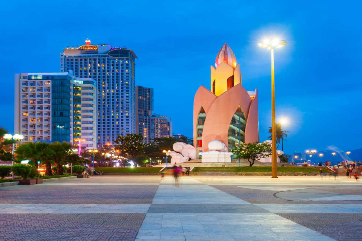 Evening Tram Huong Tower with city lights Tram Huong Tower lit in golden hues surrounded by a vibrant city backdrop under a blue twilight sky