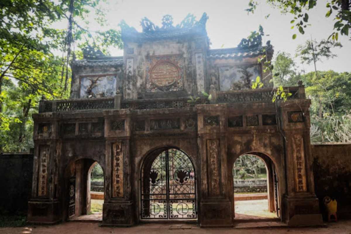 Front Gate Detail of Tu Hieu Pagoda Close-up of the weathered front gate of Tu Hieu Pagoda, showing ancient carvings and moss-covered surfaces.