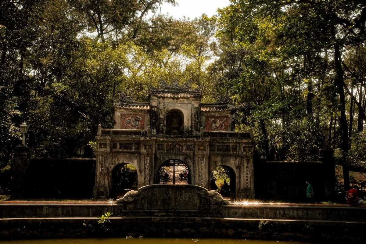 Tranquil Gate of Tu Hieu Pagoda Stone gate of Tu Hieu Pagoda bathed in warm afternoon light, surrounded by tall forest trees.
