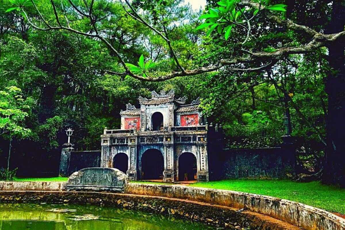 Triple-Gate Entrance at Tu Hieu Pagoda The triple-arched gate of Tu Hieu Pagoda surrounded by pine trees and reflected in a lotus pond.