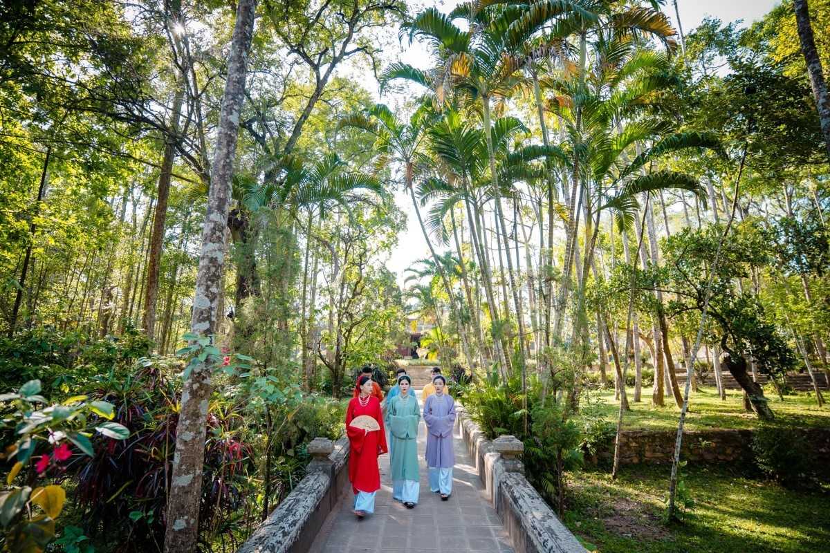 Visitors in Ao Dai at Tu Hieu Pagoda Vietnamese women in traditional Ao Dai walking through the garden path toward Tu Hieu Pagoda in Hue.